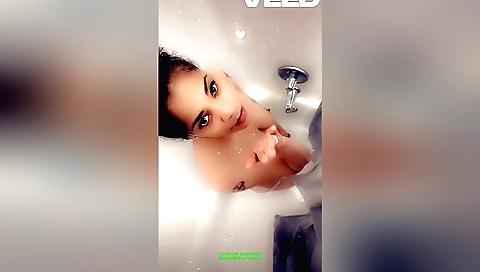 Indian showering in a white bikini on a small wooden bathtub